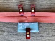 two pieces of pink and blue fabric on top of a wooden table with red handles