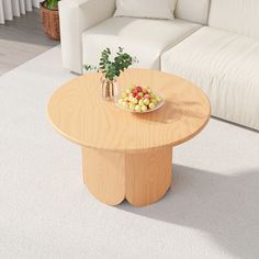 a bowl of fruit sits on a table in front of a white couch and coffee table