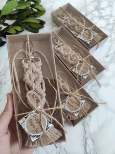 three boxes with tags and twine on them sitting on a marble counter top next to some plants