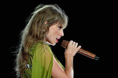 a woman in a green dress singing into a microphone