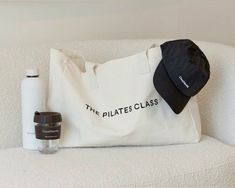 a tote bag, water bottle and other items are sitting on a white couch