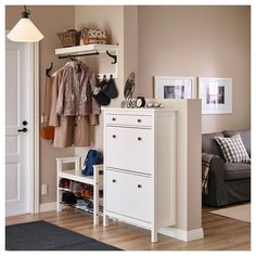 a living room filled with furniture and a coat rack on top of a white cabinet