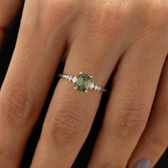 a woman's hand with a ring on it and an emerald stone in the middle