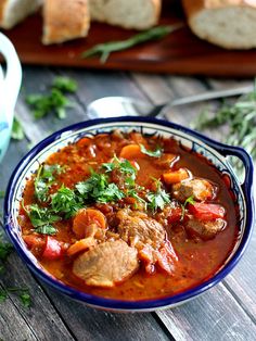 a bowl filled with meat and vegetables next to bread