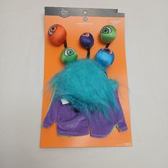 an orange and purple package with two stuffed animals on it's back, sitting on top of a white surface