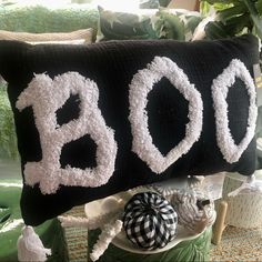 a black and white pillow with the word boo on it sitting next to other decorative items