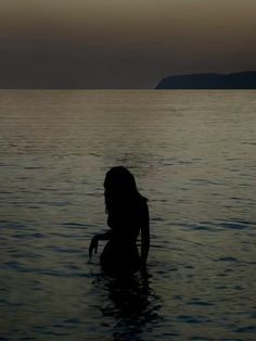 the silhouette of a woman in the water with her hand up to her face and head