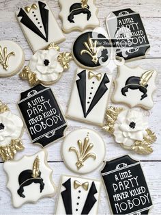 decorated cookies with black and gold accents on white wood planks are arranged in the shape of tuxedos