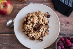 a white plate topped with granola next to fruit