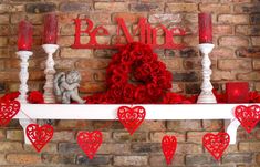 valentine's day mantle with red roses, candles and heart decorations on brick wall