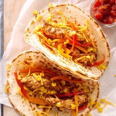 two tacos with chicken, peppers and corn on top