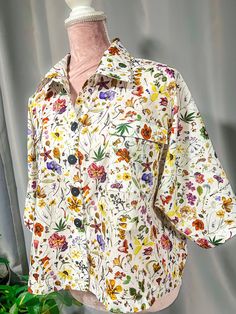 a white shirt with multicolored flowers on it and a pink mannequin