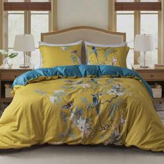 a bed with yellow and blue comforters in front of two lamps on either side of the bed