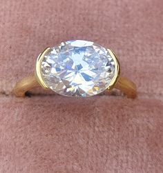 a diamond ring sitting on top of a pink velvet covered surface with a gold band