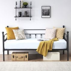 a daybed with pillows and blankets on it in a living room next to a wall