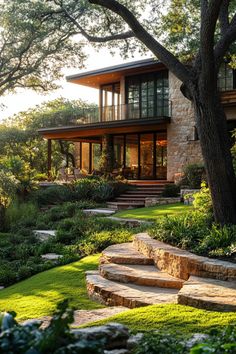 a house that is surrounded by trees and grass with steps leading up to the front door