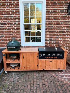 an outdoor bbq grill sitting on top of a wooden table next to a window