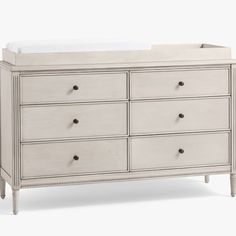 a white dresser with drawers and a baby crib in the top right hand corner