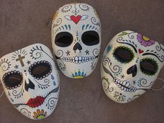 three sugar skull masks are sitting on the ground