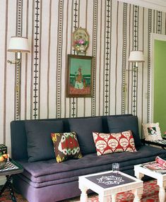 a living room filled with furniture next to a wall covered in vertical striped wallpaper