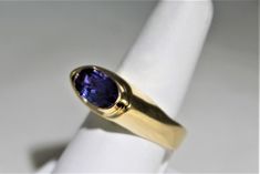 Wow--WOW--TANZANITE This is a eye catching genuine Tanzanite ring. We set this 3.5 carat oval across the finger and it is gorgeous. The 3.5 carat stone is a deep purple with blue overtones ,a choice stone. The stone is 20 mm long and 9 mm wide and is set with bezel ends . This protects the stone from damage. I call the my saddle style ring with a European style shank. the squared bottom keeps the top form spinning over. Currently a size 6 it can be size up or down 1 size, please inquire about pr Modern Sapphire Ring Oval Cabochon For Formal Occasions, Oval Sapphire Ring Stamped 14k For Formal Occasions, Formal Oval Sapphire Ring Stamped 14k, Modern Oval Tanzanite Sapphire Ring, Oval Tanzanite Ring For Formal Occasions, Formal 14k Gold Oval Sapphire Ring, Formal Oval Sapphire Ring In 14k Gold, Formal Oval Tanzanite Ring, Oval Amethyst Ring In 14k Gold With Brilliant Cut