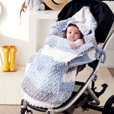 a baby in a stroller with a blanket on it's back, wrapped in a blue and white blanket