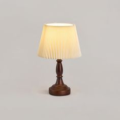 a wooden table lamp with a white shade on the top and bottom part of it