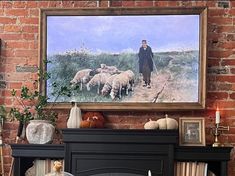 a man is walking with his sheep in front of a painting on a brick wall