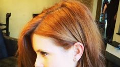 a woman with red hair is looking at her cell phone while she sits in the salon