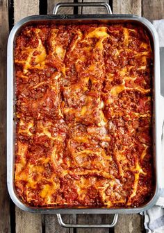 a casserole dish with meat and cheese in it sitting on a wooden table