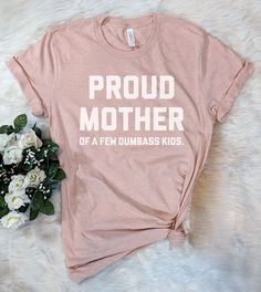 This "Proud Mother Of A Few Dumbass Kids" design is the perfect funny shirt for Mom! Makes a great Birthday Day gift or Mother's Day present! Funny Pink T-shirt With Text Print, Father's Day Pink T-shirt With Letter Print, Novelty Pink Crew Neck T-shirt, Funny Text Tops For Fan Merchandise, Pink Novelty T-shirt With Funny Print, Novelty Fan Merchandise T-shirt With Letter Print, Father's Day T-shirt With Funny Print, Funny Tri-blend T-shirt With Screen Print, Funny Text Tri-blend T-shirt