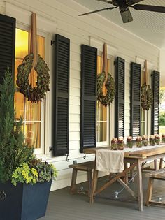 a screen shot of a porch with black shutters and potted plants on it