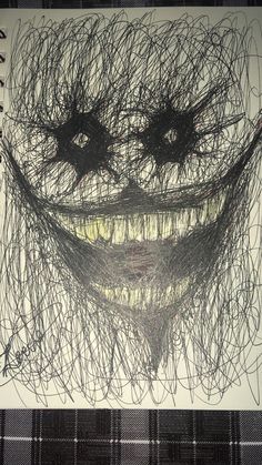 a drawing of a smiling face made out of black and white yarn on a sheet of paper