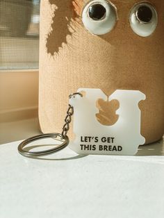 a keychain that has been placed next to a vase with eyes and the words let's get this bread on it