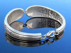 an antique silver bracelet is shown on a blue surface