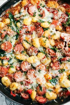 a skillet filled with lots of food on top of a stove burner and covered in cheese