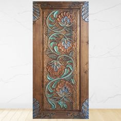 an intricately carved wooden panel with flowers and leaves on the side, against a white wall