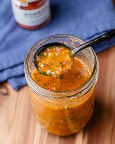 a spoon full of soup sitting on top of a wooden table next to a blue towel