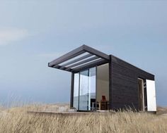 a small black house sitting on top of a dry grass covered field next to tall brown grass