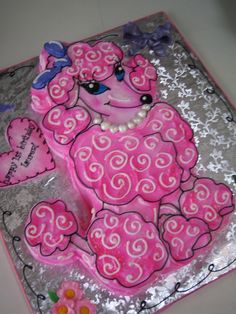 a birthday cake with pink frosting and hearts on it's side, decorated like a poodle