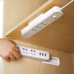 a person is holding an electronic device in front of a wall mounted power strip with two outlets