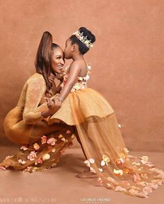 two women are sitting on the ground with petals all around them and one is kissing the other's cheek