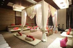 a room filled with lots of white couches covered in pink and red pillows next to tables