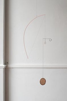 a white room with a clock hanging from the ceiling and a wire attached to the wall