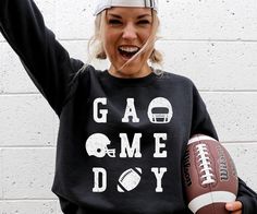 a woman holding a football and wearing a sweatshirt that says gad me doy