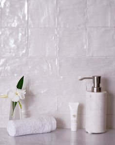 a bathroom counter with white towels, soap dispenser and flowers