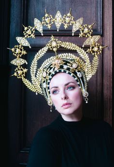 This wonderful golden halo headdress is a truly special statement piece! The 'Frida' halo is made from a soft base of black chenille and velvet, adorned with beautiful golden filigrees and pearls. Crystals twinkle here and there to further catch the light and add to the drama of this piece.  Made to order - please allow for some variation in the creation of this headdress. Trim/crystals may vary. High Crown Gold Headpiece For Festival, Gold High Crown Headpiece For Festivals, Gold Structured Crown Headpiece For Festival, Gold Ceremonial Headpiece With Round Crown, Gold Ceremonial Headpiece With Tall Crown, Gold Tall Crown Costume Hat, Gold Costume Hat With Tall Crown, Elegant Gold Costume Hats And Headpieces For Ceremonial, Gold Crown Headpiece For Festivals