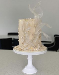 there is a white cake with gold decorations on the top and bottom, sitting on a table