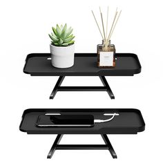 two black trays with plants on them and an electronic device sitting on one side