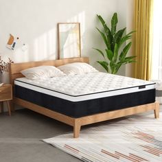 a bed with a wooden frame and mattress in a room next to a potted plant